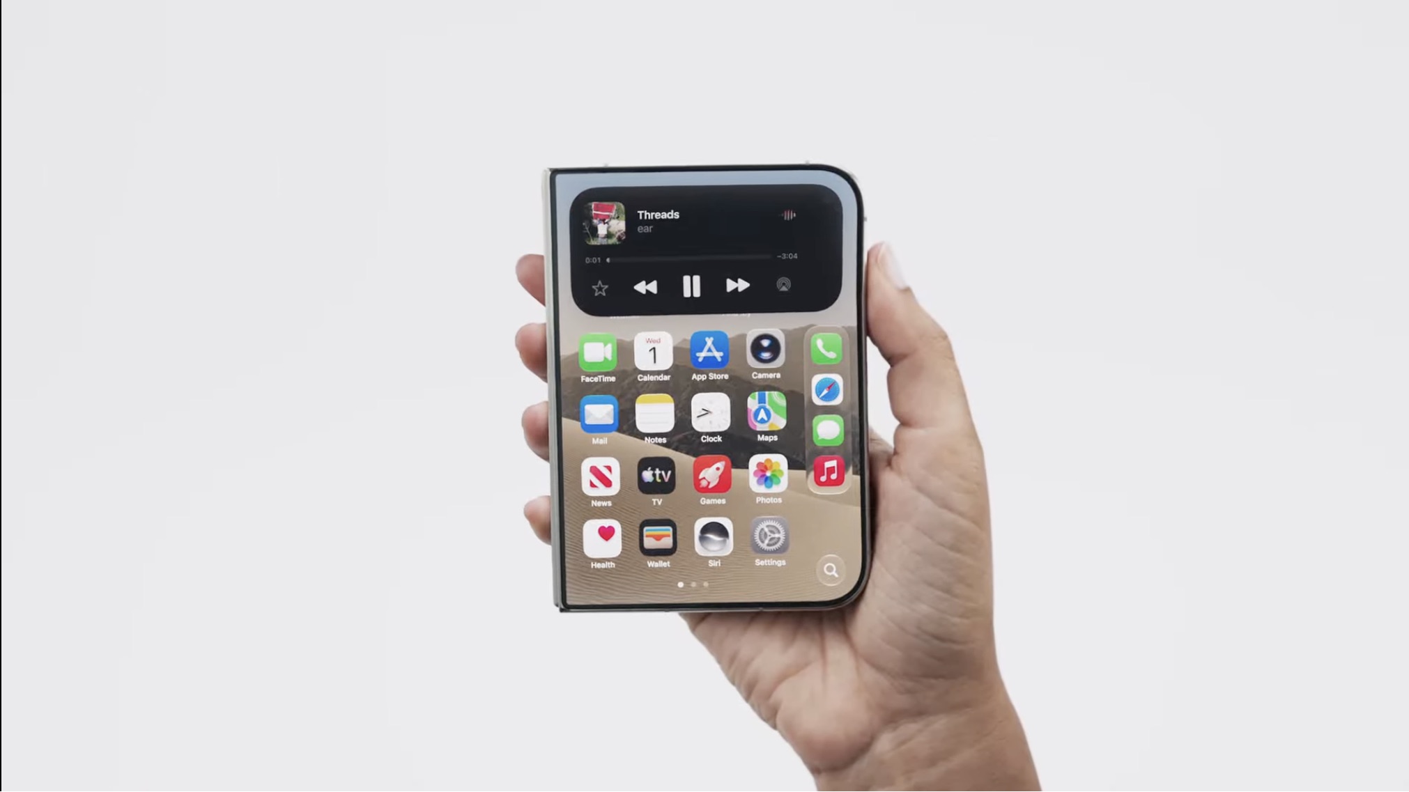 Uma mão segura um smartphone dobrável fechado, exibindo a tela externa com ícones de aplicativos e um widget de mídia no topo, contra um fundo branco neutro.